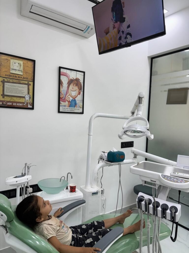 A child relaxing in the dental chair at North Delhi Dental Clinic, watching cartoons on the ceiling-mounted TV